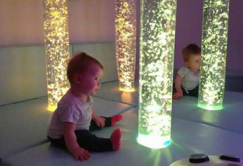 Baby interacting with colored bubble tubes at the Science Zone in Bournemouth