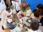 A group of kids with lab coats and goggles making experiments with the teacher 